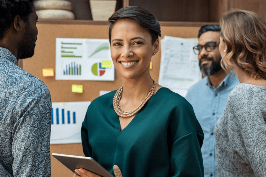 Successful businesswoman standing with her staff in background at modern office.