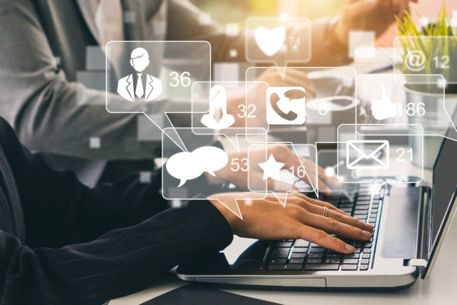 Business computer with social media engagement graphics rising from keyboard