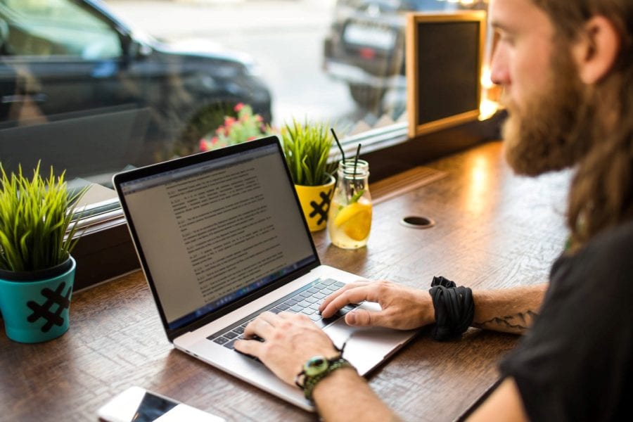A content marketer typing on a laptop in a café