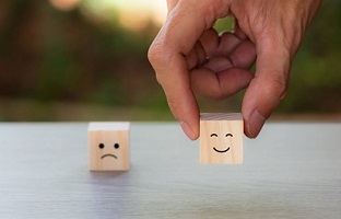 Wooden blocks with sad and happy faces, signifying customer satisfaction