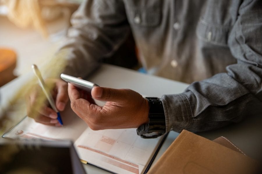 Man holding a phone and his planner, developing his organisational skills