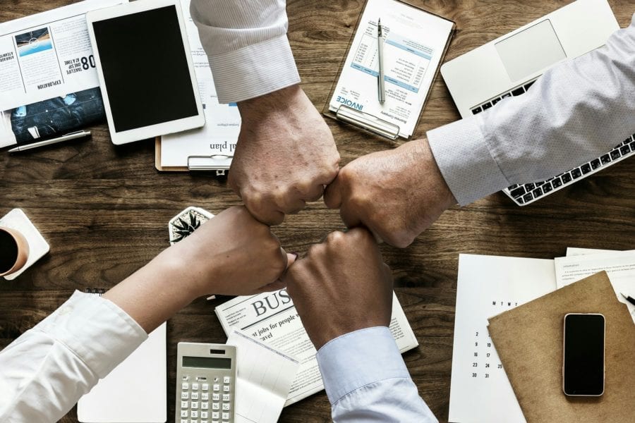 A team coming together and fist bumping while discussing business results
