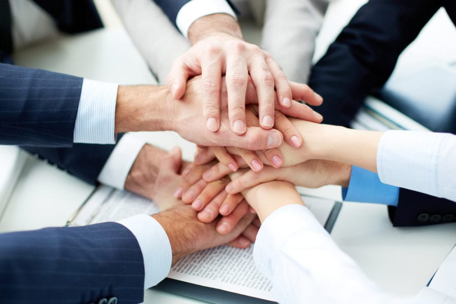 Close-up of business partners making pile of hands at meeting