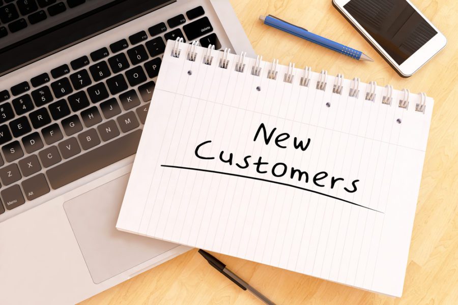 New Customer - handwritten text in a notebook on a desk