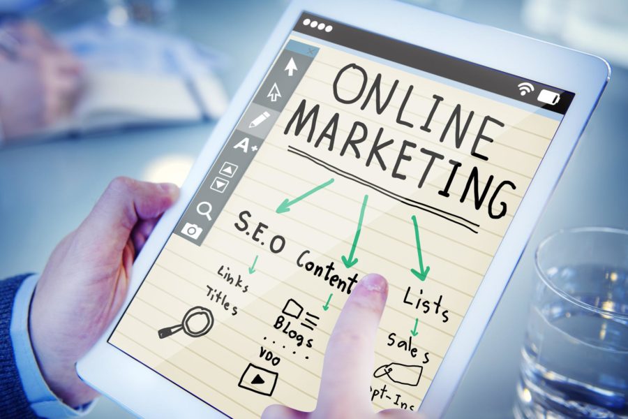 A business owner holding a tablet displaying the words Online Marketing and ideas