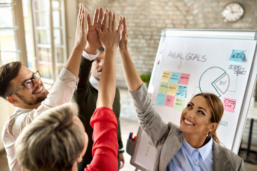 Happy business team with raised hands celebrating their success in the office