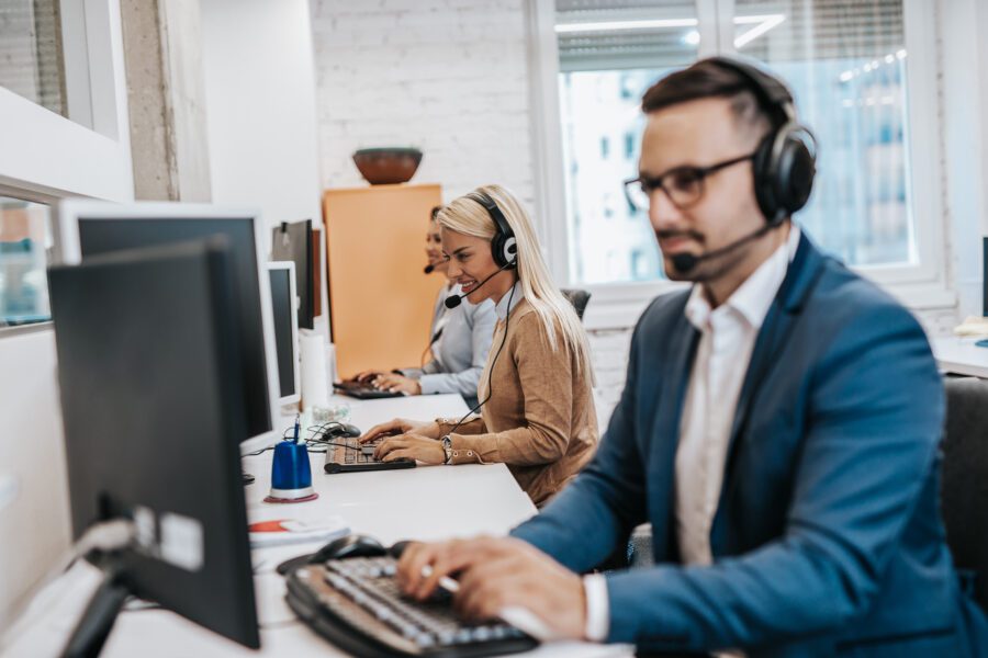 Photo of a male customer service agent with headset working in call centre.