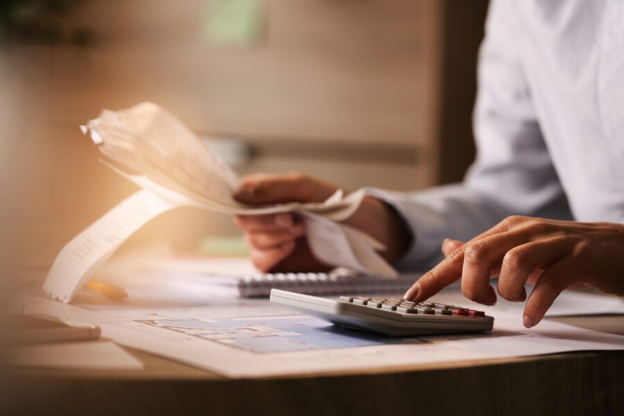 Closeup of economist using calculator while going through bills and taxes