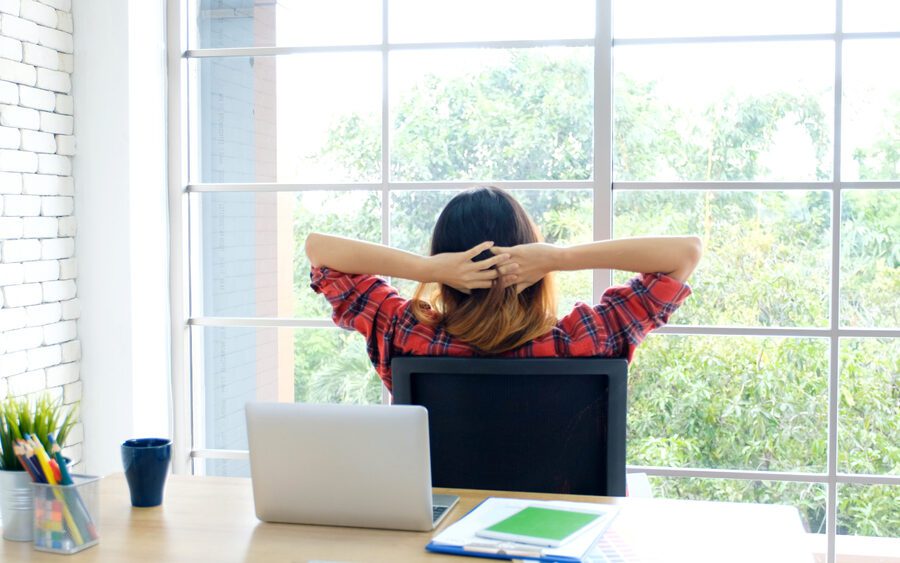 Young woman stretching body while working with laptop computer at her desk home office.