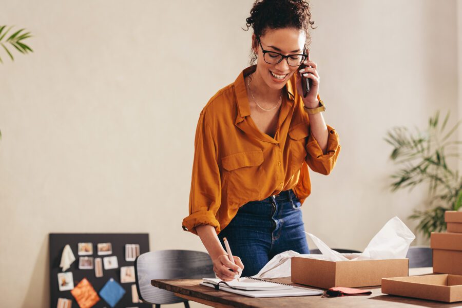 A female entrepreneur working at a home office confirms an order on the phone.