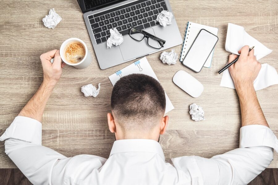 top-view-tired-overworked-businessman-office-worker-lying-desk-with-laptop-coffee-papers