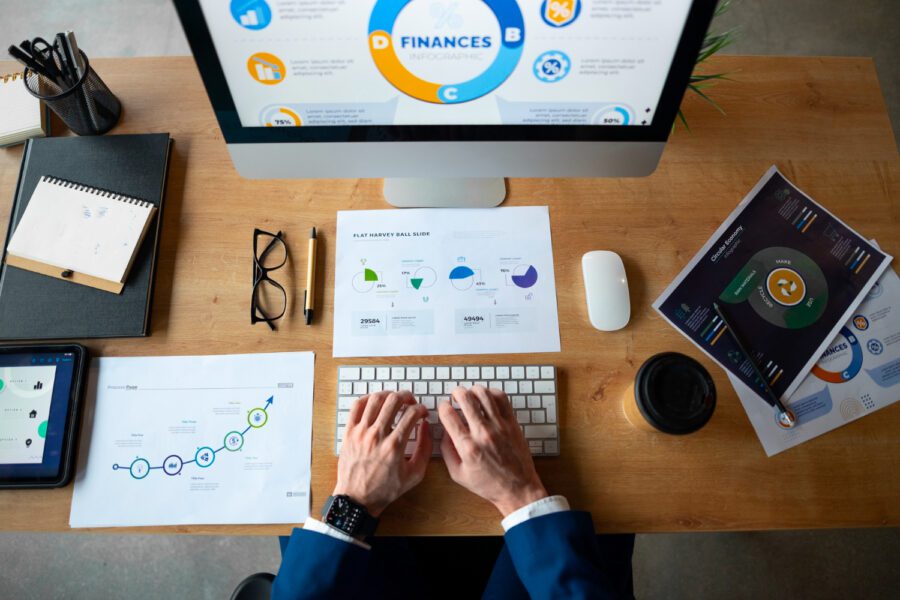 A person typing on a keyboard with financial papers on the desk.