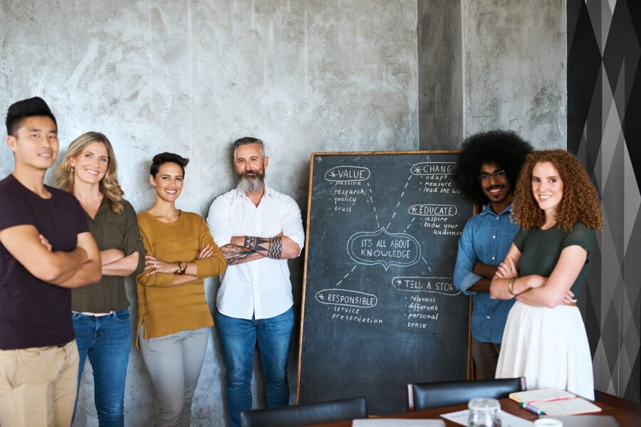 Cropped portrait of a group of employees standing with their arms folded in an office.