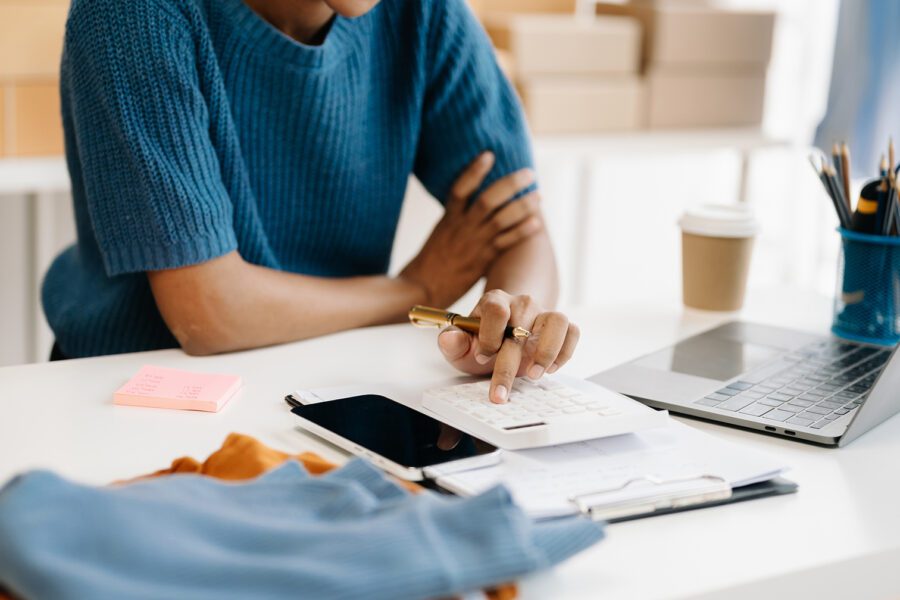 Startup small business SME, Entrepreneur owner woman using a smartphone or tablet, taking receipts and checking online purchase shopping orders to prepare and pack product boxes.