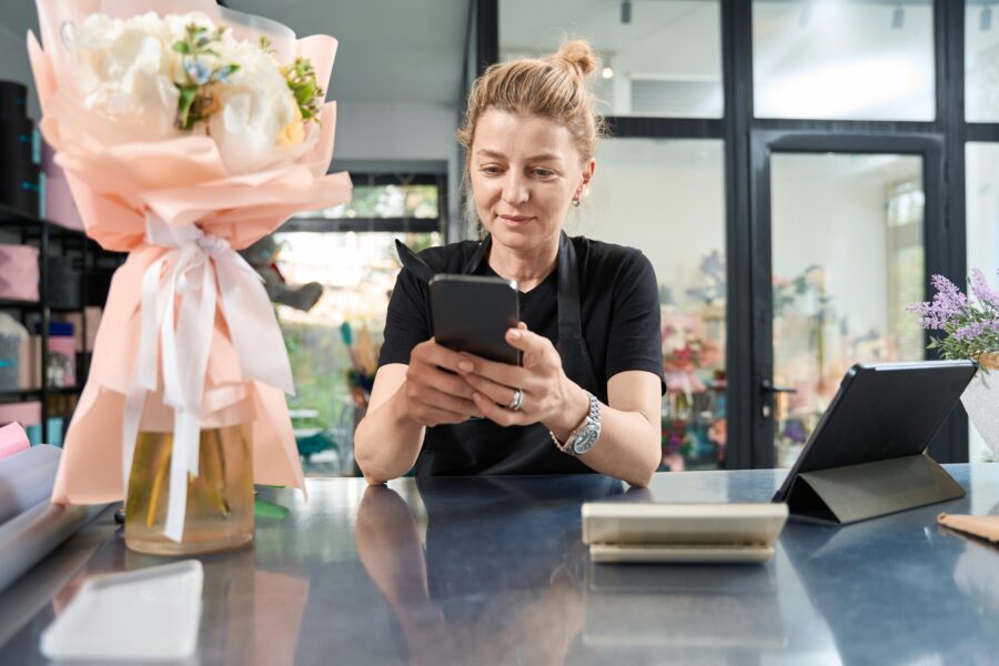 Happy florist sitting at counter chatting with customers on phone