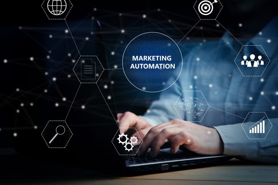 A person typing on a laptop with marketing automation and icons on a virtual screen.