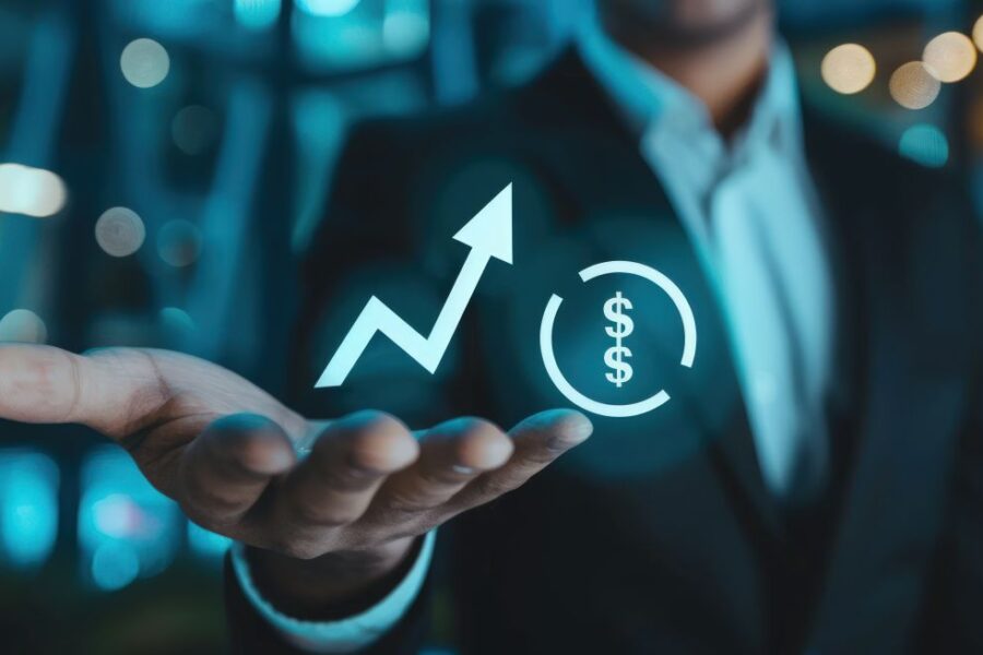 Photograph of a person in a suit holding a holographic upward-trending arrow and a dollar sign symbol, representing financial growth or business success.